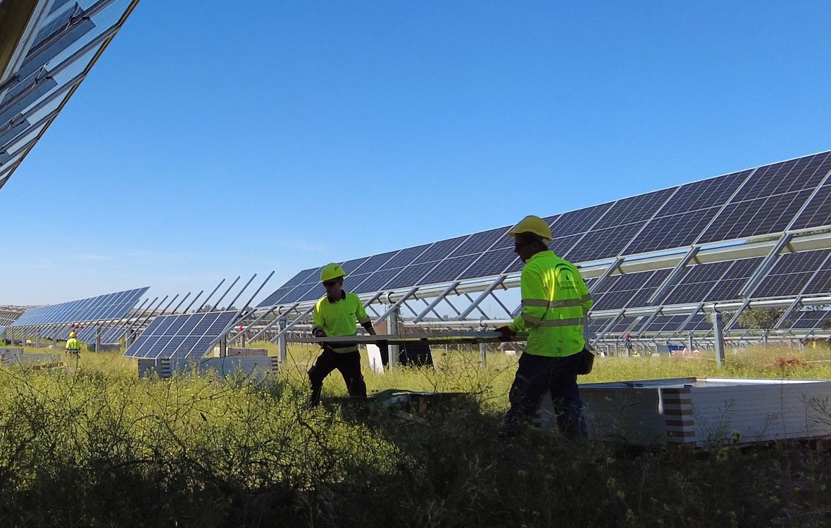 two workers next to a solar panel on a field